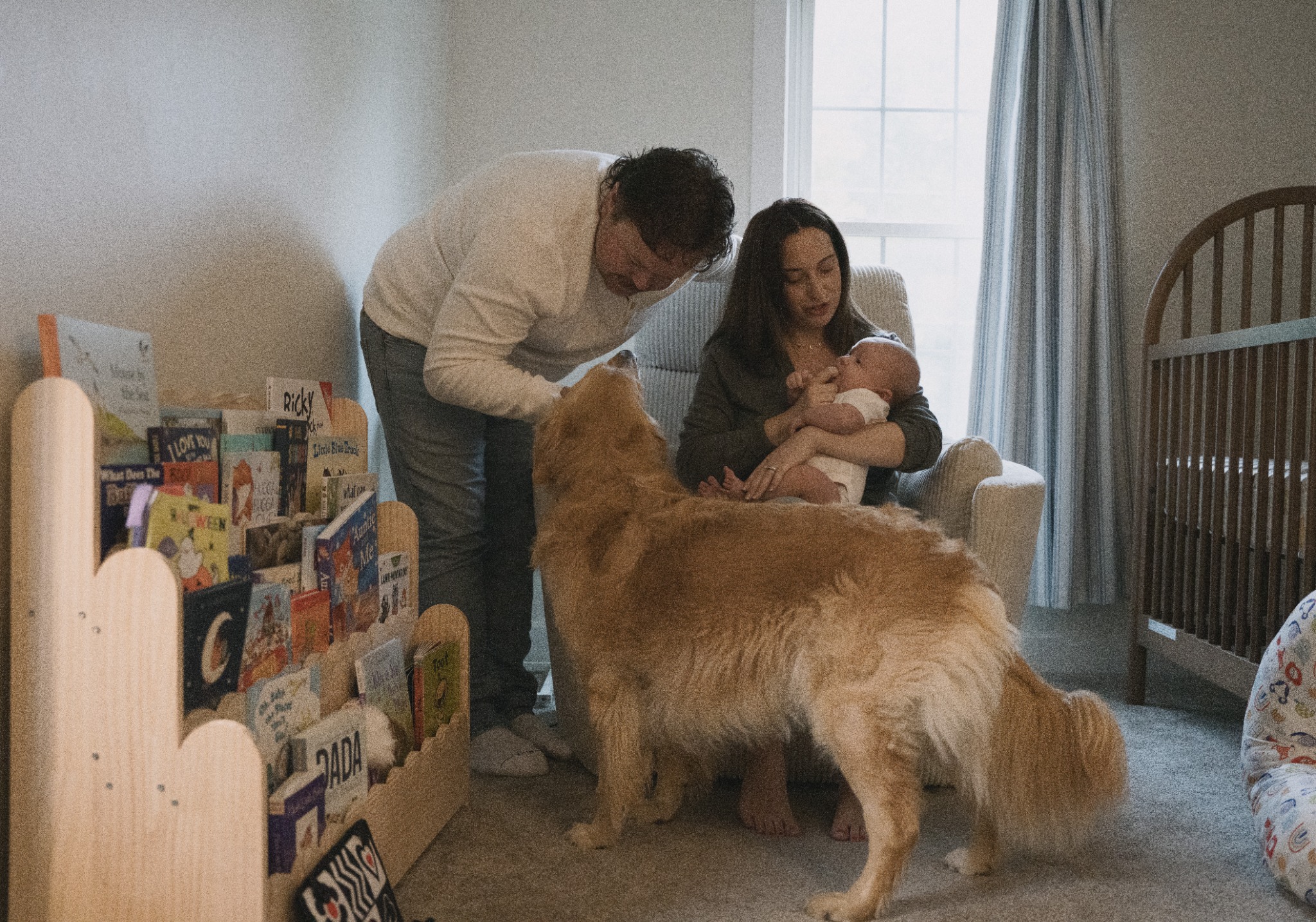 Parents with their newborn and dog in their nursery during an at-home family session